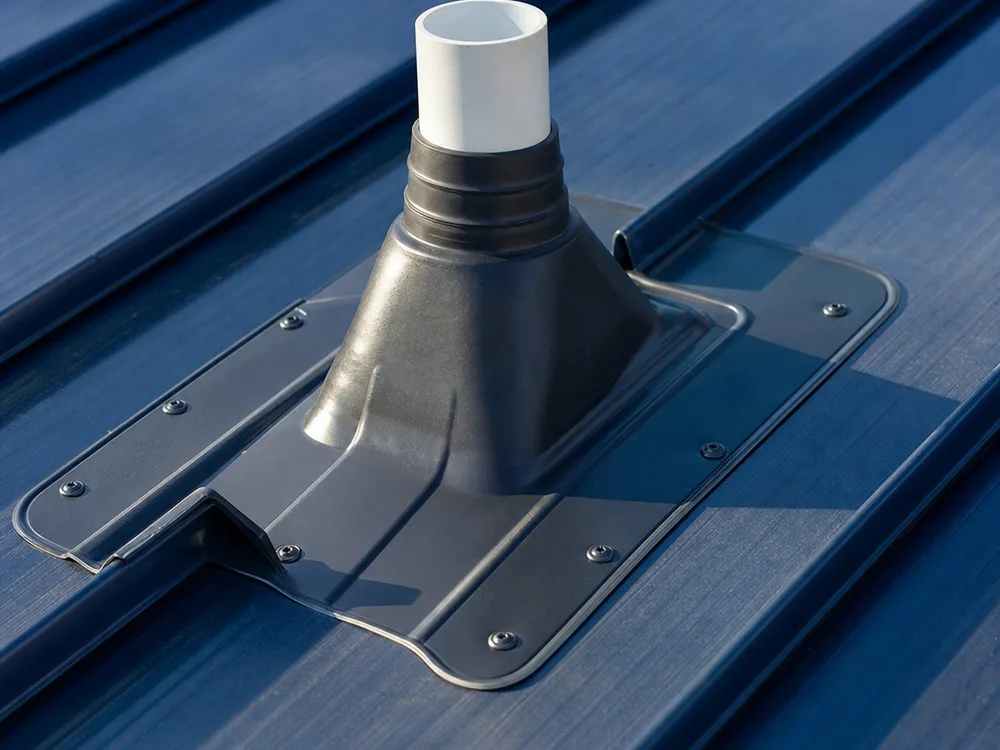 Close-up of a residential roof penetration with properly installed flashing, a sealed vent boot, clean fastener placement, and visible edge details